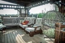 Уютная беседка с мягкой мебелью и плетеным креслом