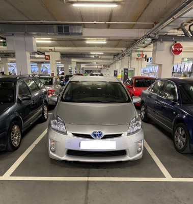 Серебристый автомобиль Toyota в парковке между другими машинами